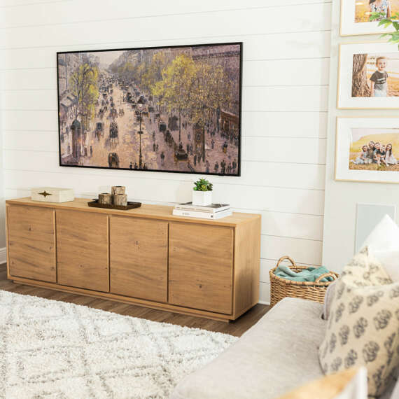 TV on top of wood furniture with white carpet and white cushions and shite sofa