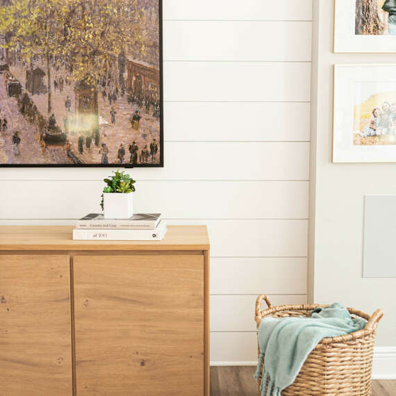 basket next to wood furniture under tv on white wall