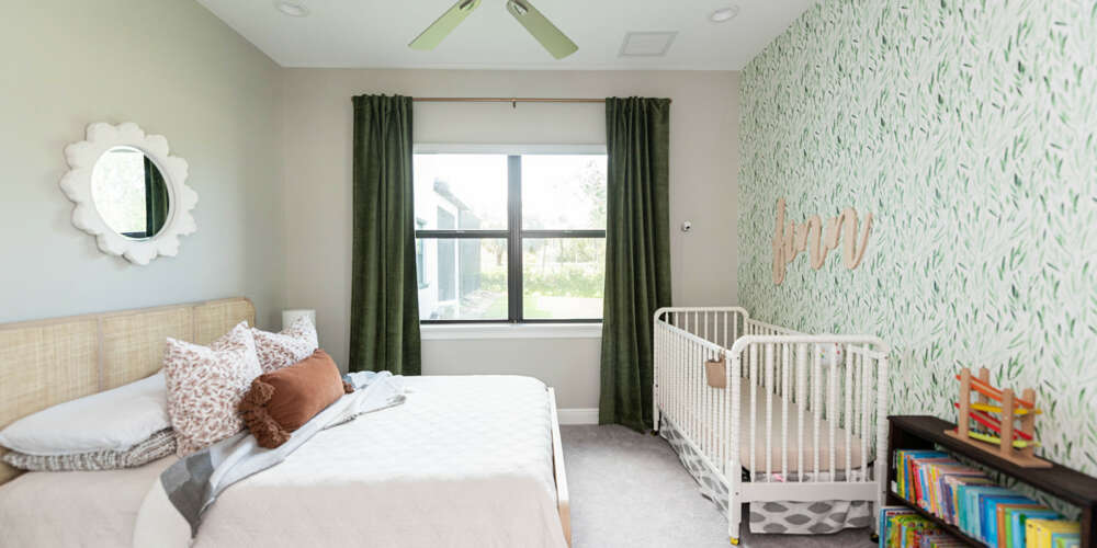 Light green walls bedroom with ceiling fan, a double size bed whit light wood headboard and white cradle