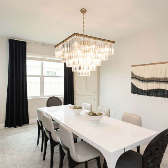 Light walls dining room-White dining table with dark chairs-dark curtains-dark furtinure-gold frame circle shape mirror-ashen wood floor-ceiling hanging lamp