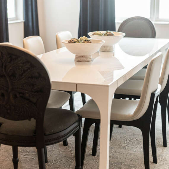 Light walls dining room-White dining table with dark chairs-dark curtains-dark furtinure-gold frame circle shape mirror-ashen wood floor-ceiling hanging lamp