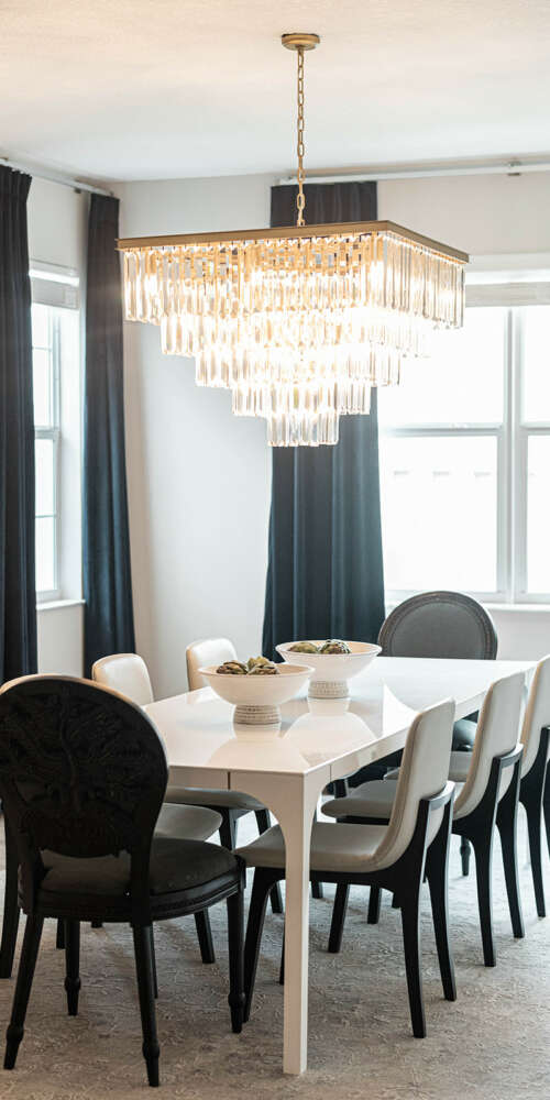 Light walls dining room-White dining table with dark chairs-dark curtains-dark furtinure-gold frame circle shape mirror-ashen wood floor-ceiling hanging lamp
