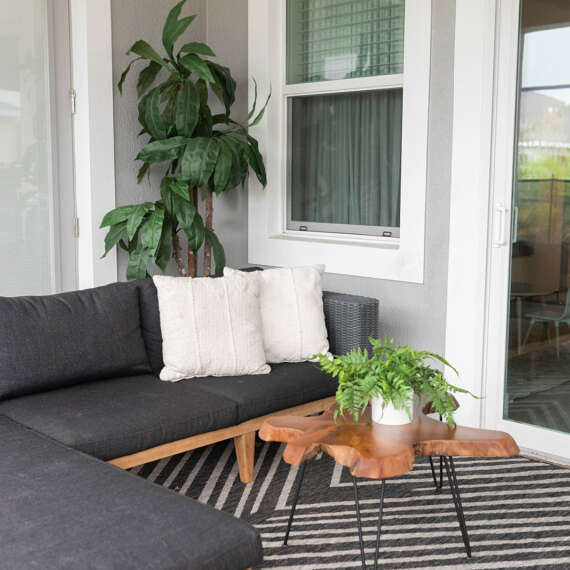 Dark patio sofa, geometrical with light and dark stripes carpet, tree trunk shape coffe table