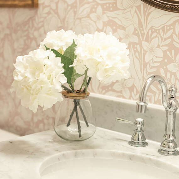 Clear glass vase with white flowers-floral light wallpaper-light marble sink